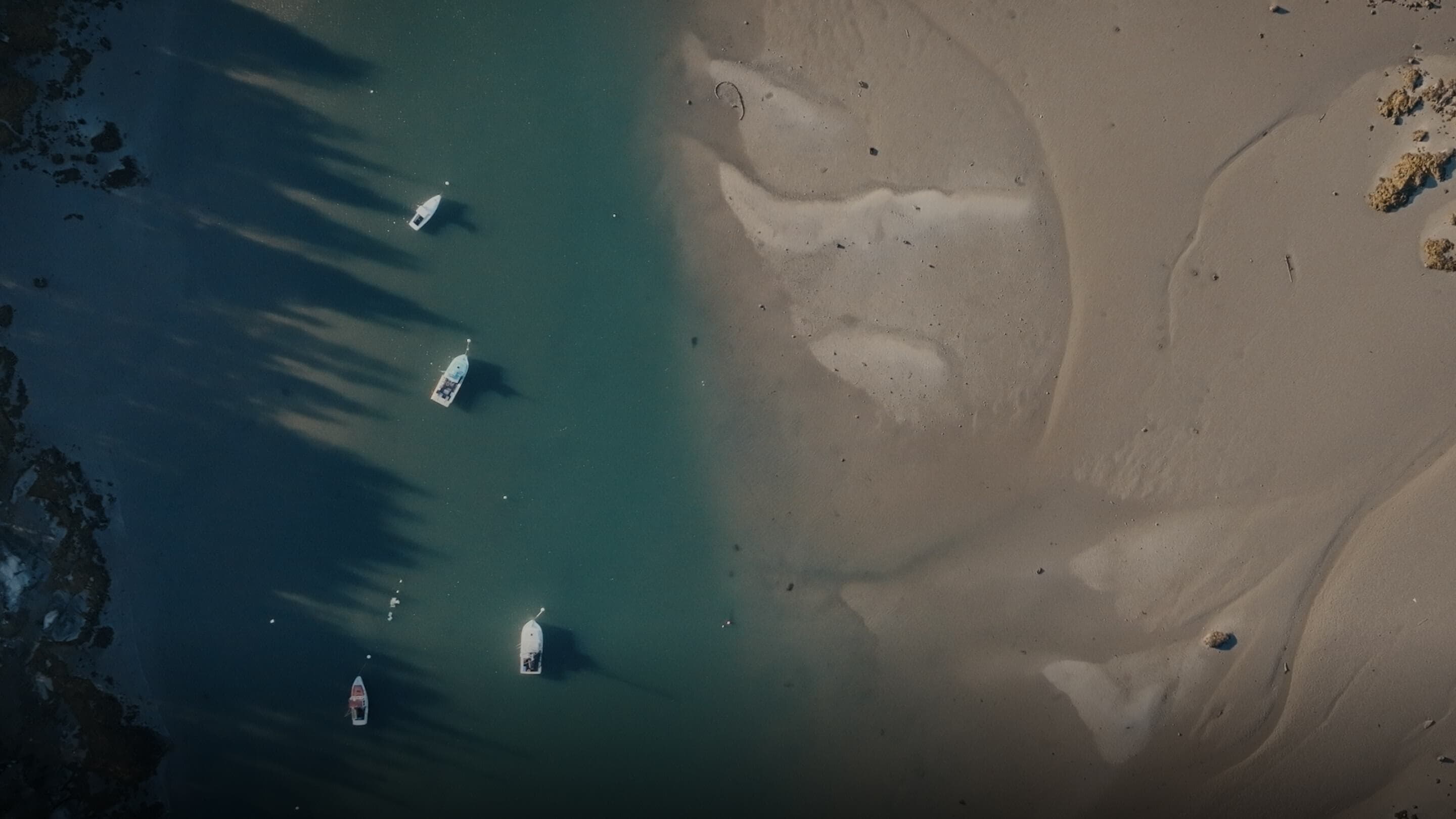Boats on clear water near sandy shore, showcasing nature and the need to address plastic waste.