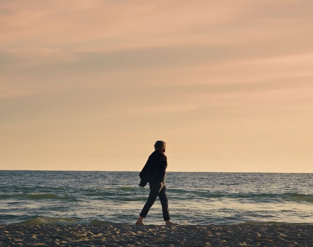 A researcher walks on a beach, reflecting on the need to reduce the use of plastic.
